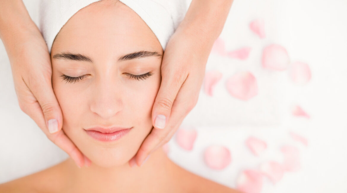 attractive woman receiving facial massage spa center